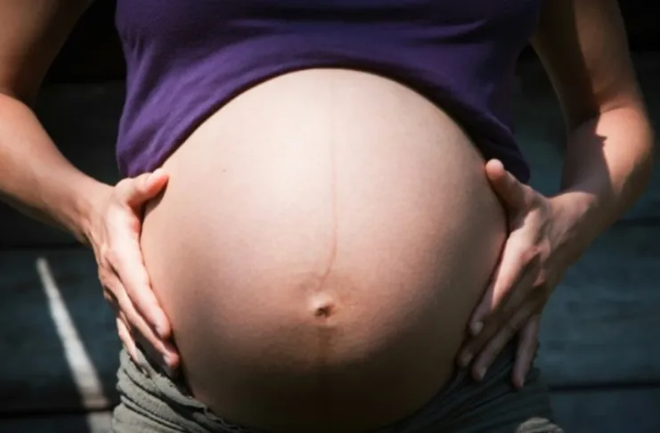 primer plano de una panza de embarazo avanzado sosteniendo con ambas manos de cada lado